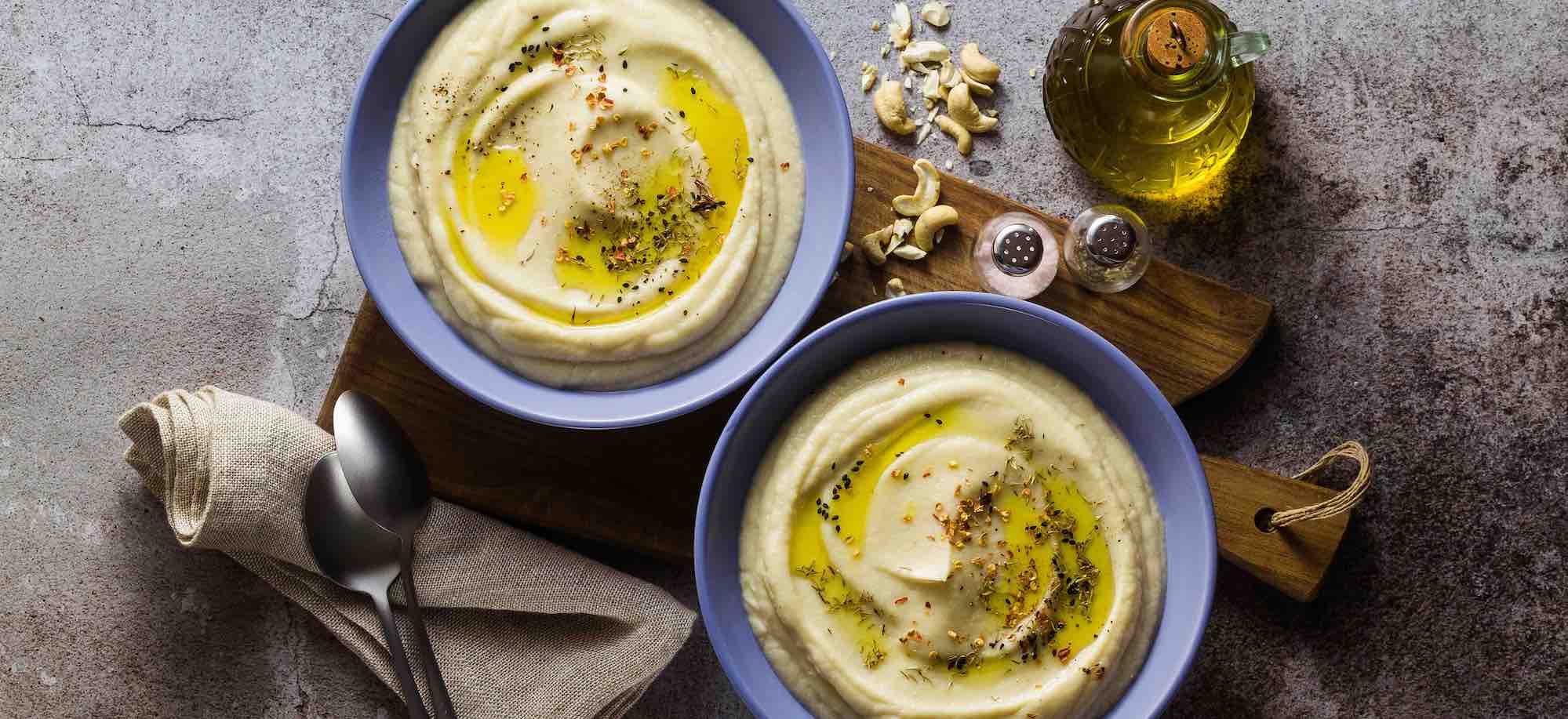 two bowls of mashed cauliflower with spices as garnish